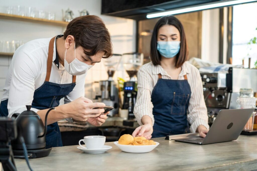 Asian Barista couple enjoy doing digital marketing in cafe restaurant.