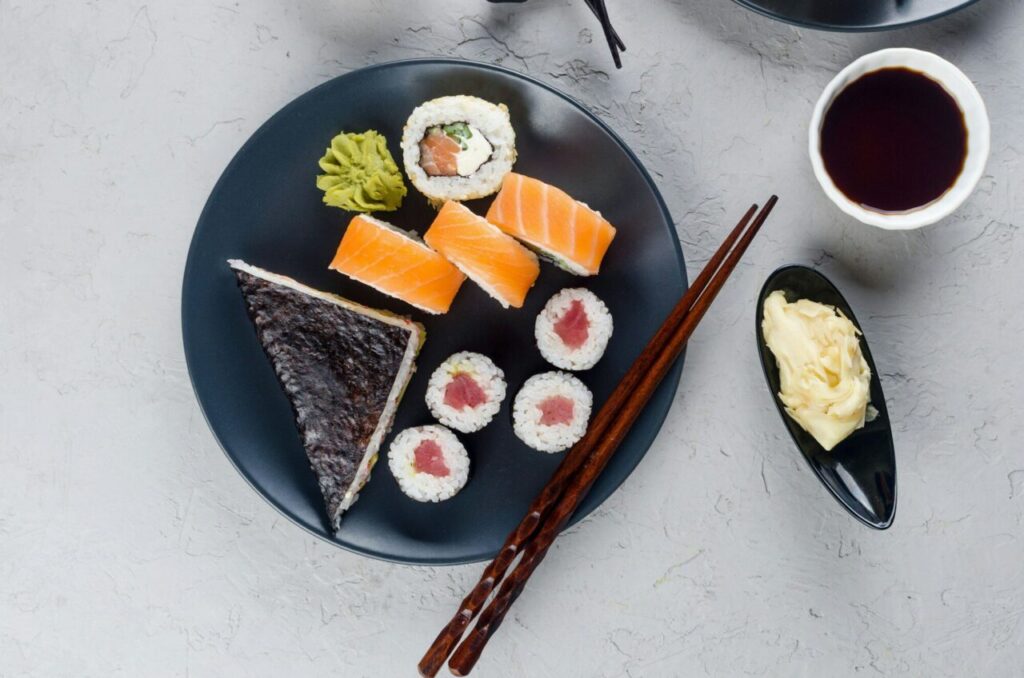 Assorted different sushi rolls on a plate and soy sauce, ginger, wasabi