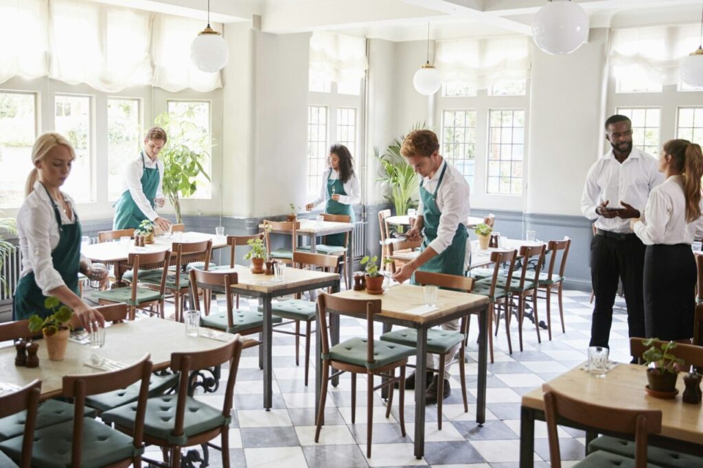 Staff Laying Tables In Empty Restaurant